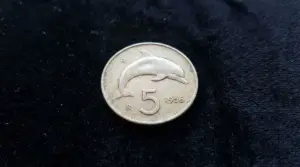 Moneta italiana da 5 lire del 1956 con delfino su sfondo nero
