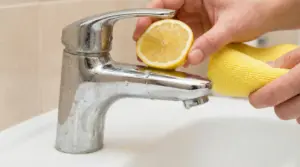 Rubinetto opaco pulito con mezzo limone e panno giallo
