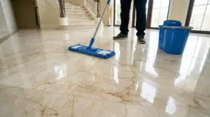 Persona che lava un pavimento in marmo lucido con un mocio e secchio blu