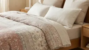 Letto con lenzuola e coperte dai toni neutri e floreali, in una camera da letto luminosa