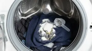 Vestiti scuri in lavatrice con detersivo in polvere versato direttamente sui tessuti