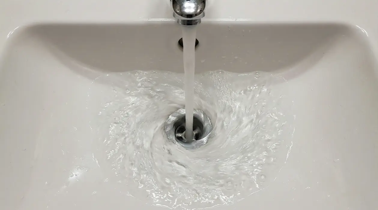Acqua che scorre nel lavandino formando un vortice in senso orario