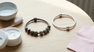 Due braccialetti Pandora, uno ossidato e uno lucido, accanto a prodotti per la pulizia su un tavolo