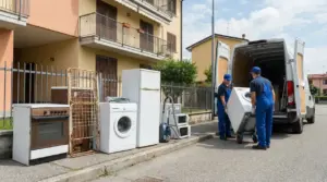Due operatori caricano un elettrodomestico usato su un furgone davanti a una casa