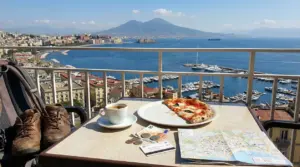 Vista su Napoli con pizza, caffè, mappa e denaro su un tavolo da terrazza